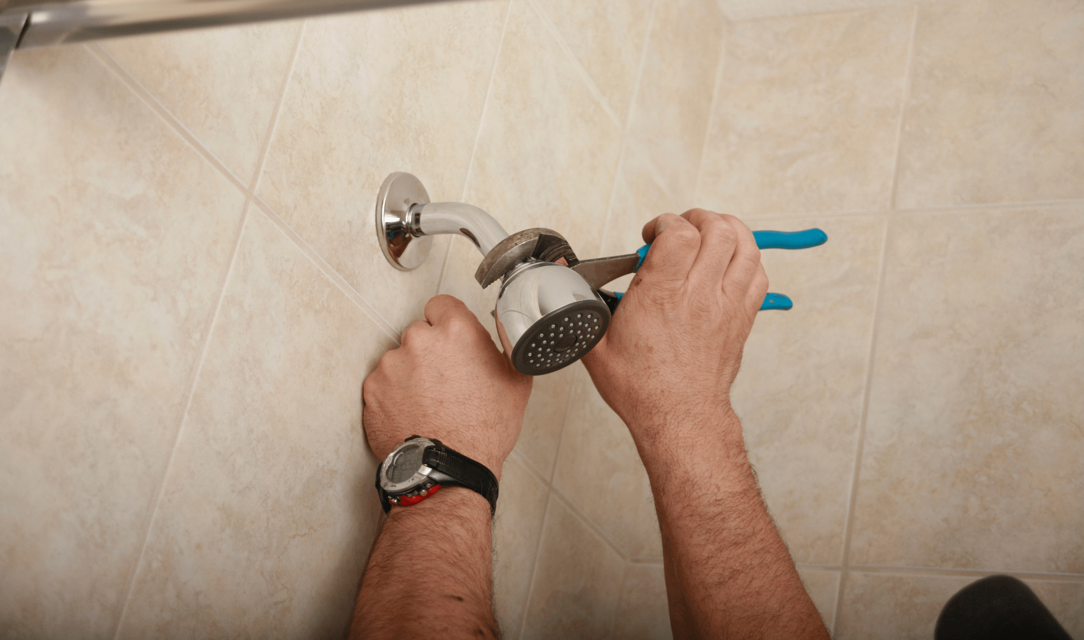 A pair of hands tightening a showerhead with an adjustable wrench.