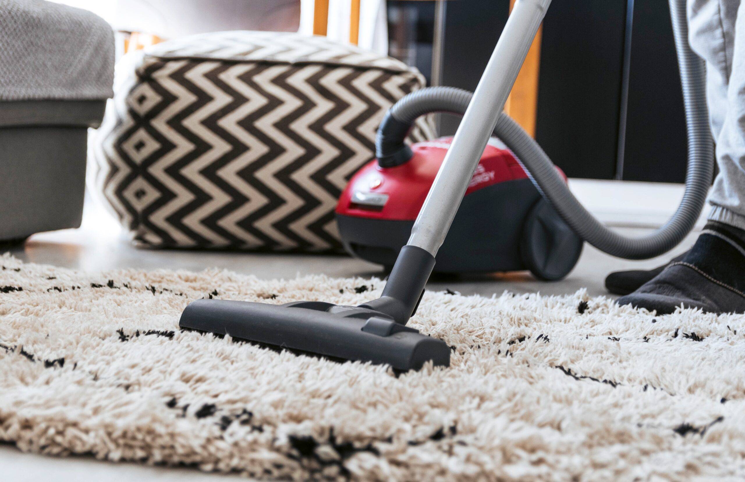 A close photo of someone vacuuming a shag rug.