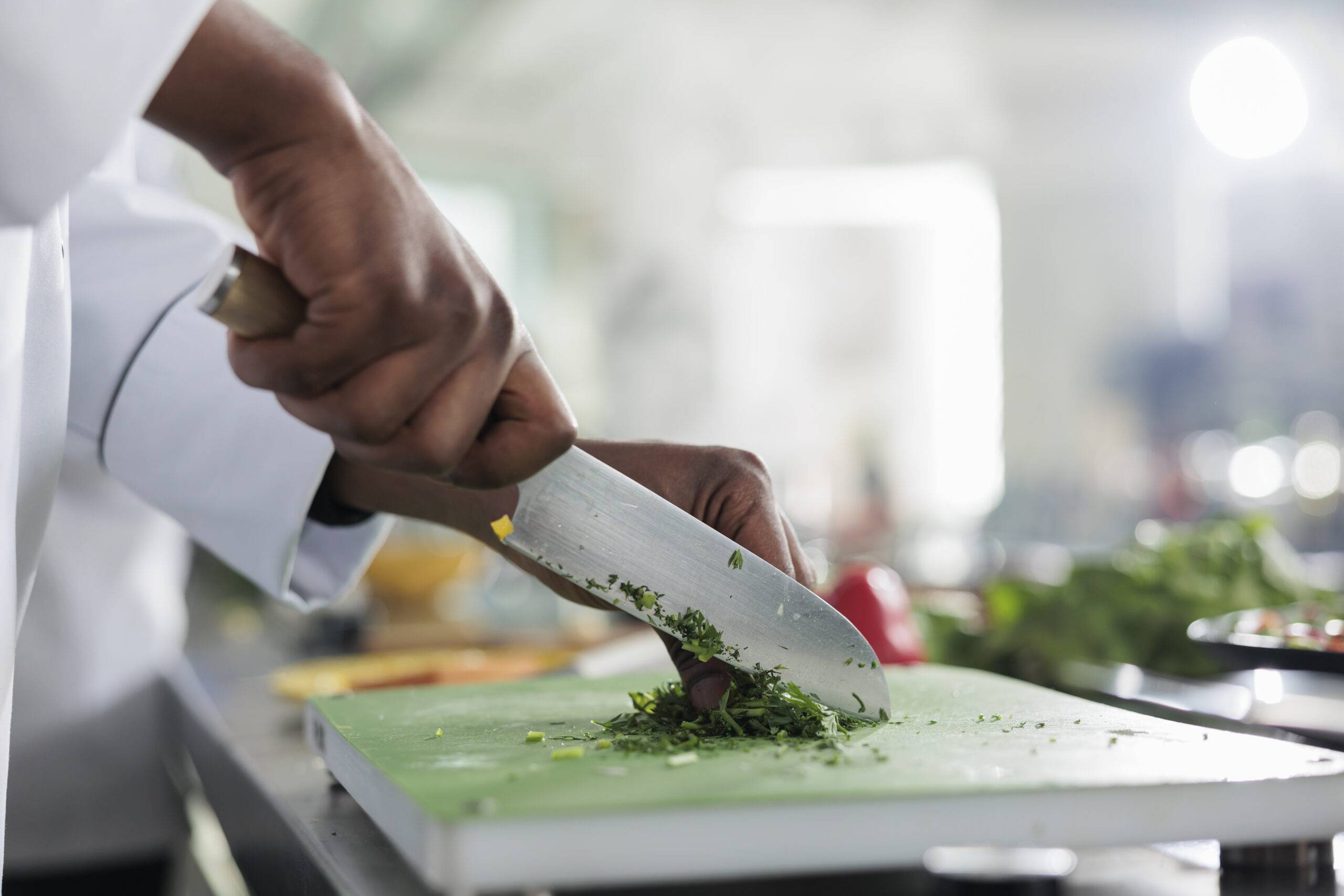 Close up of hands using professional knife to chop finely fresh organic herbs and vegetables for stew recipe. Cook cutting greens for gourmet dish served at fine dining restaurant.