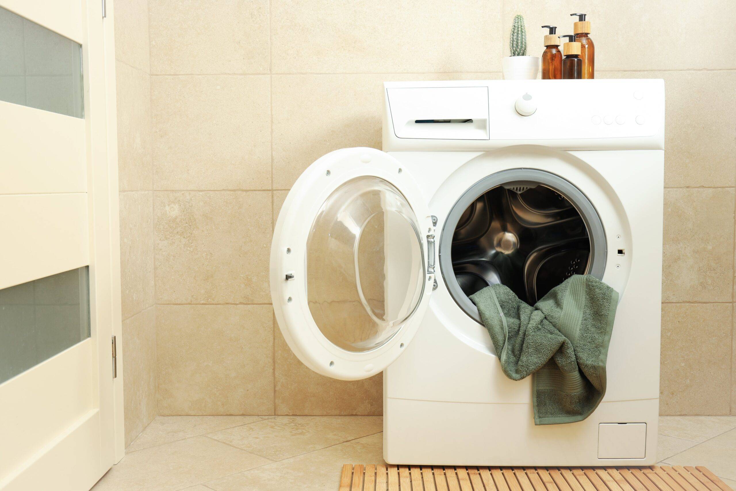 An open washing machine with a towel hanging out.