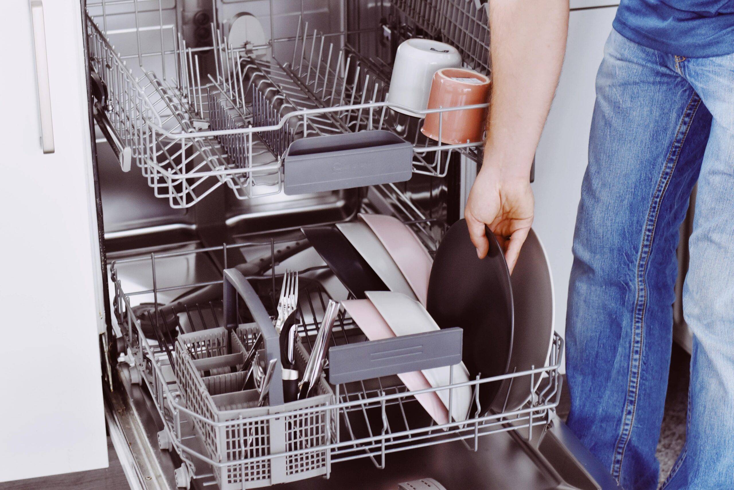 A person loading a dishwasher.