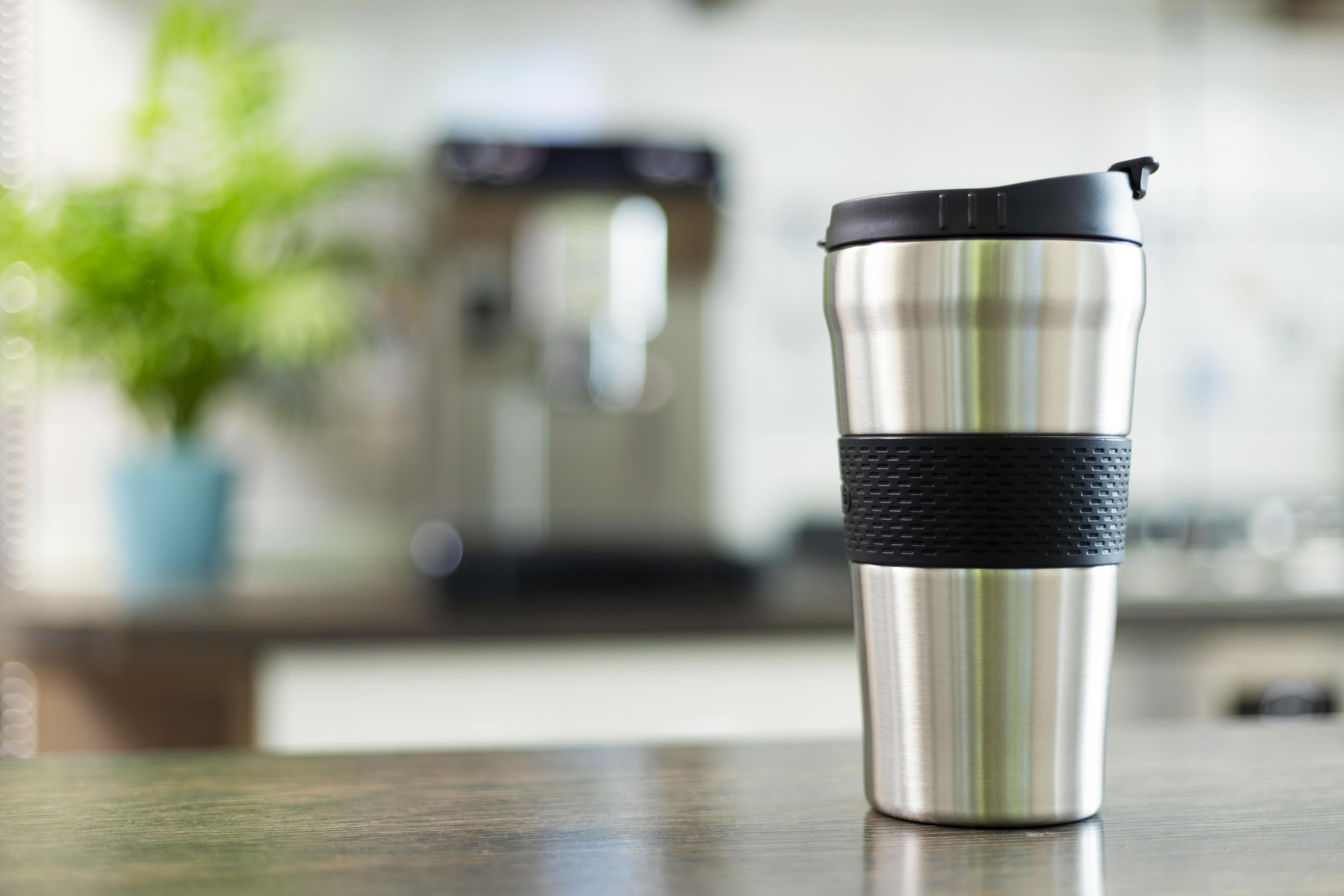 A stainless steel travel coffee mug on a counter.