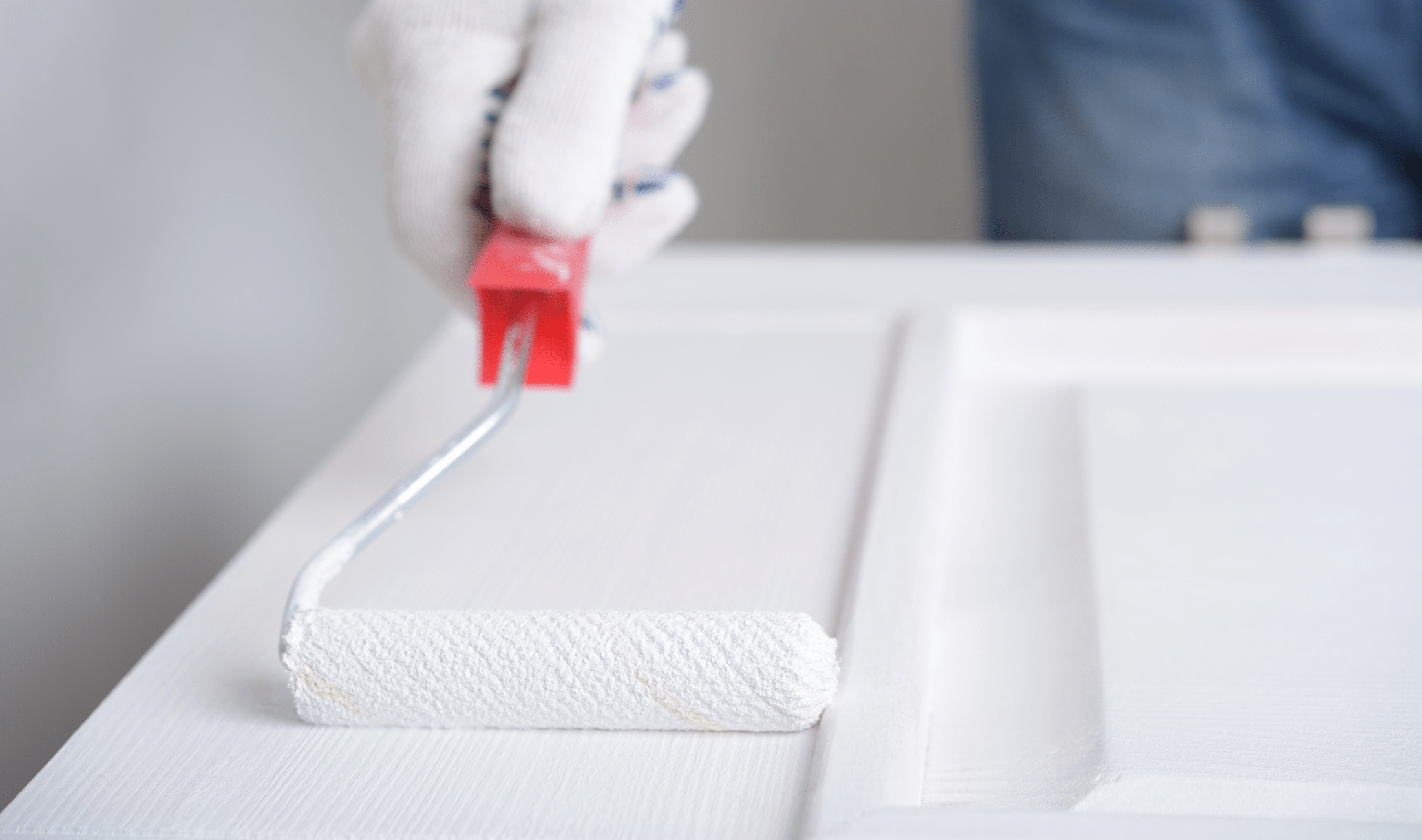 A close view of someone painting a door with a roller.
