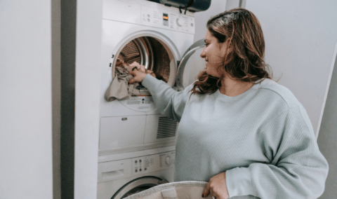 A woman loading a washing machine.