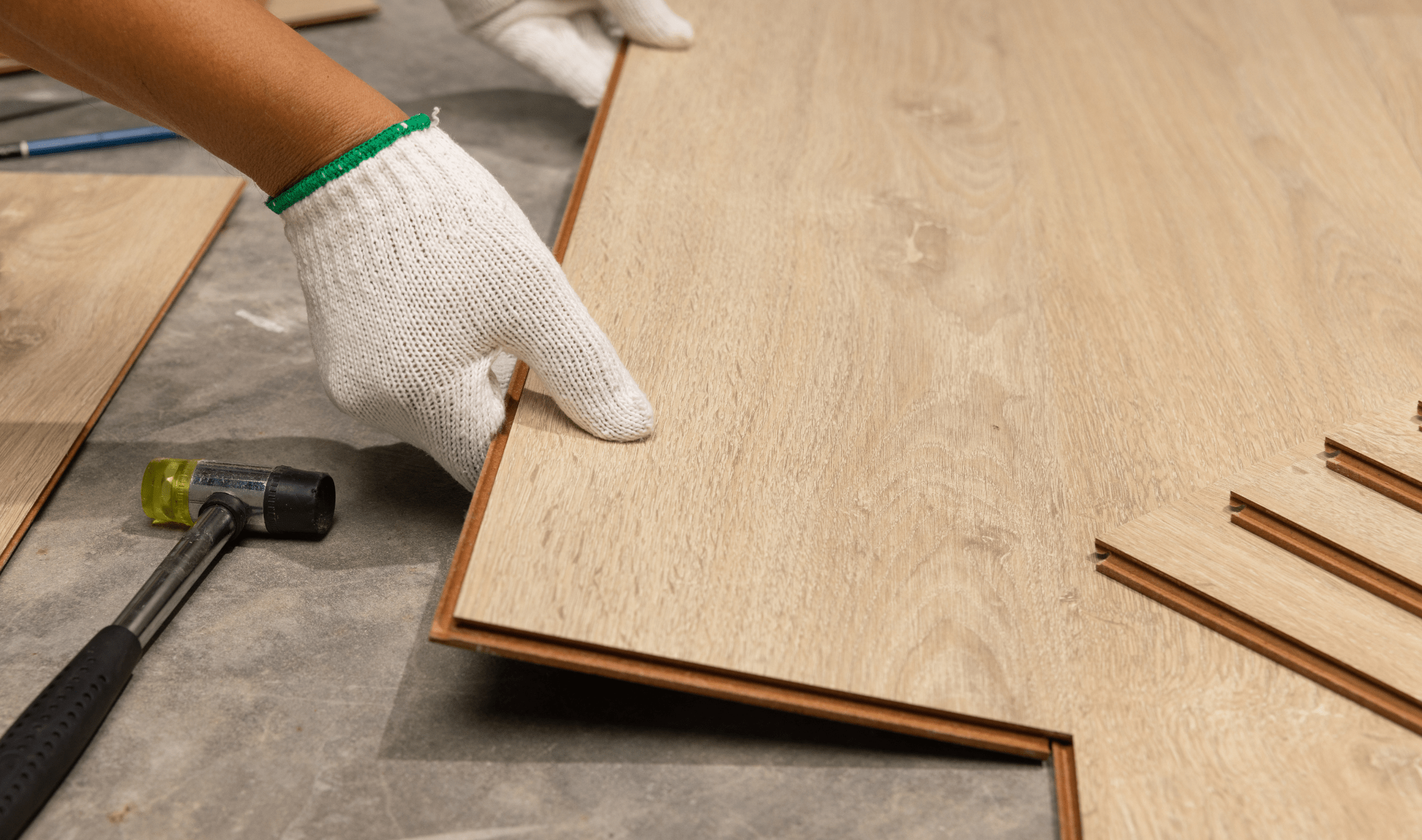 A pair of hands installing vinyl plank flooring.