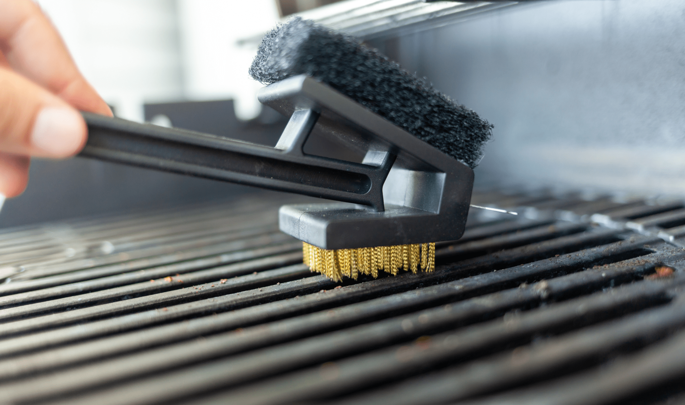 A close photo of someone cleaning a grill with an wire brush.