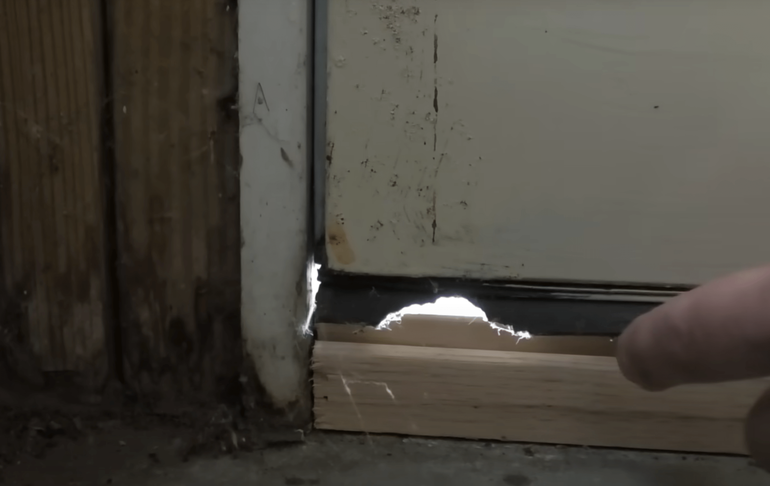 Hole in the bottom of a door seal.