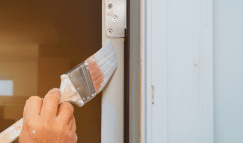 A close view of someone painting a door's edge.