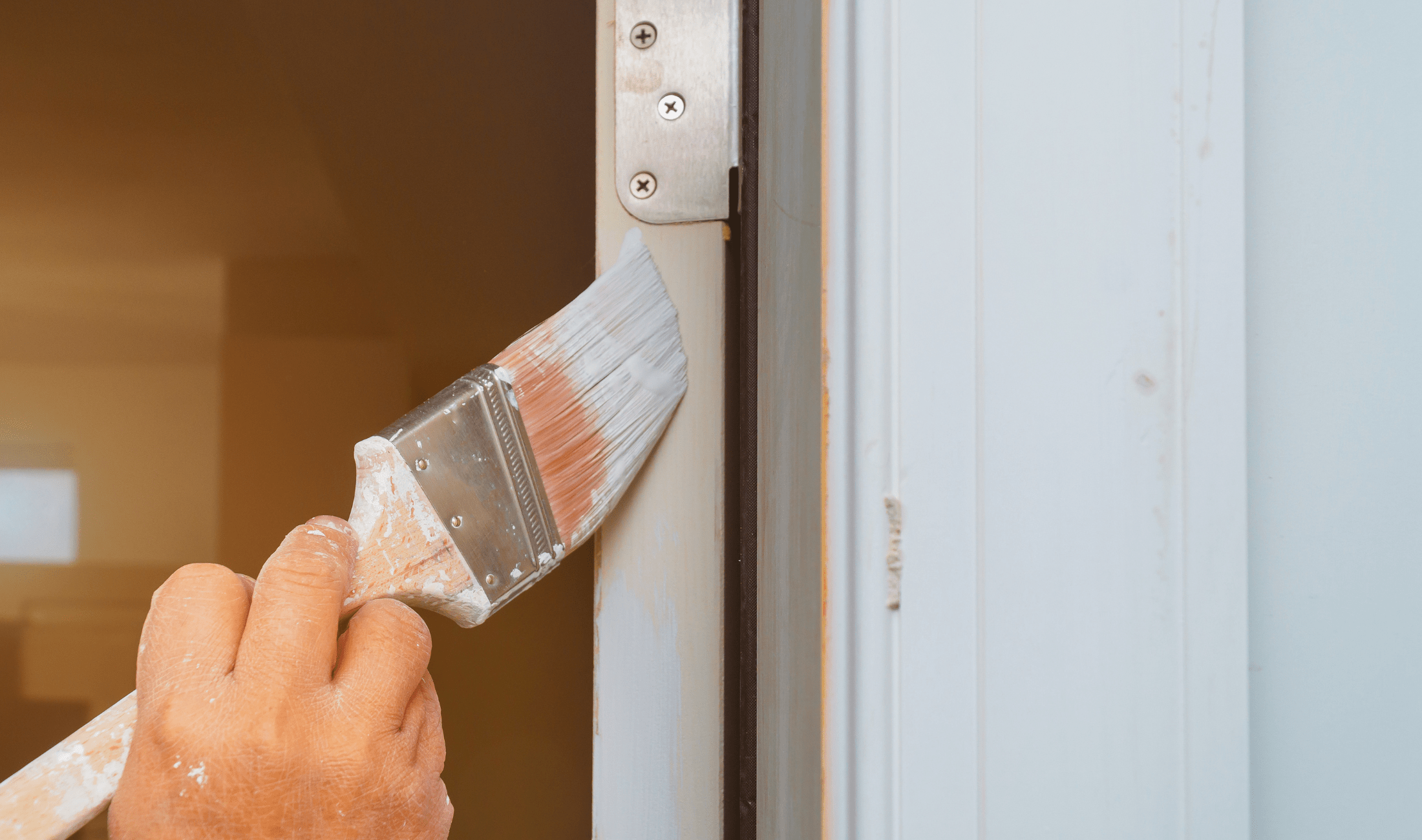 A close view of someone painting a door's edge.