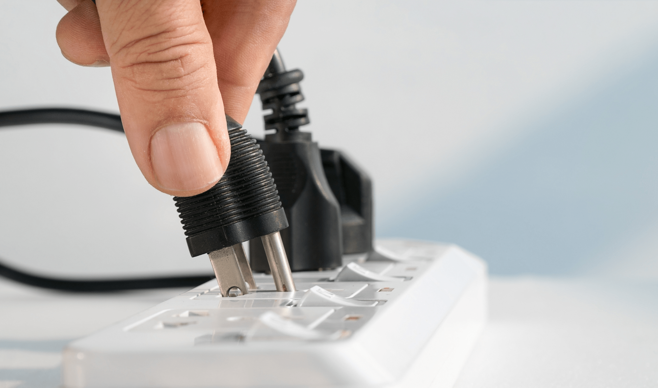 A close photo of a hand unplugging a plug from a power bar.