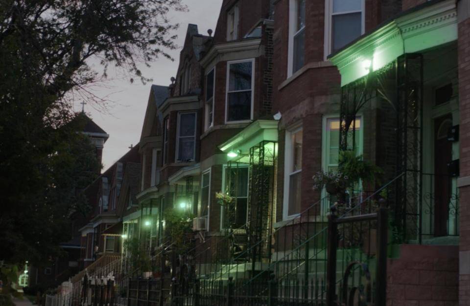 A row of townhomes, all with green lights on their porch.