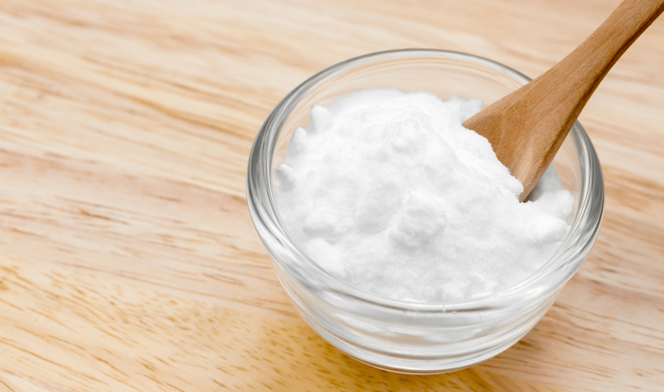 A bowl of baking soda with a wooden spoon in it.
