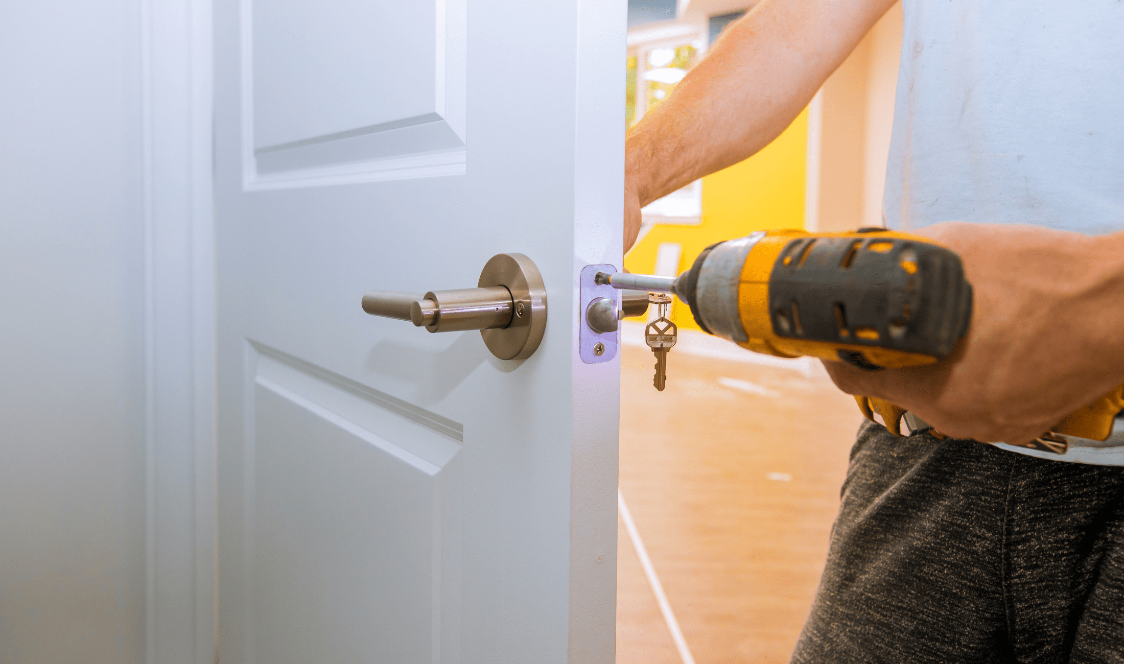 Someone drilling a stroke plate into a door.