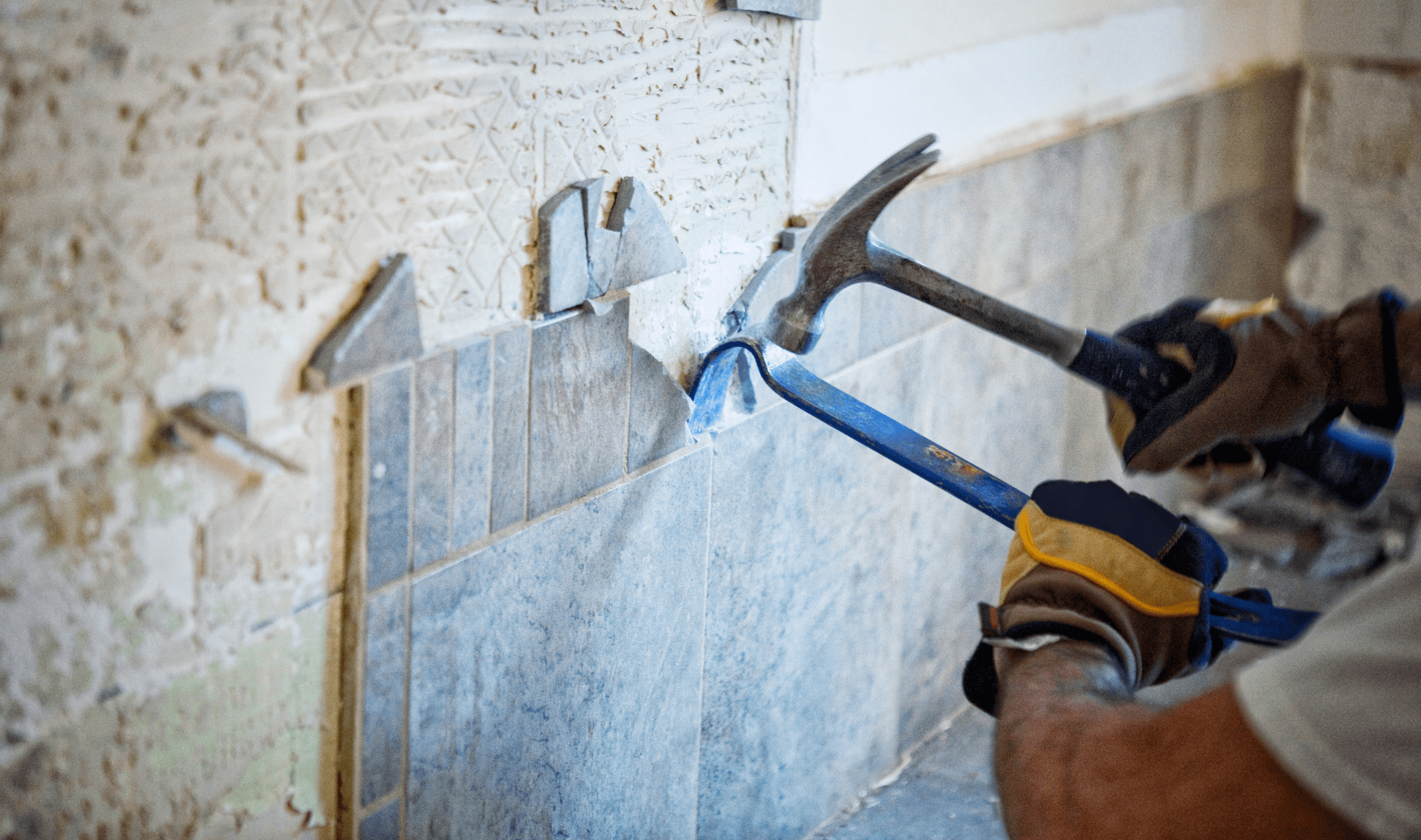 A person chiselling away at a kitchen backsplash that's being replaced.