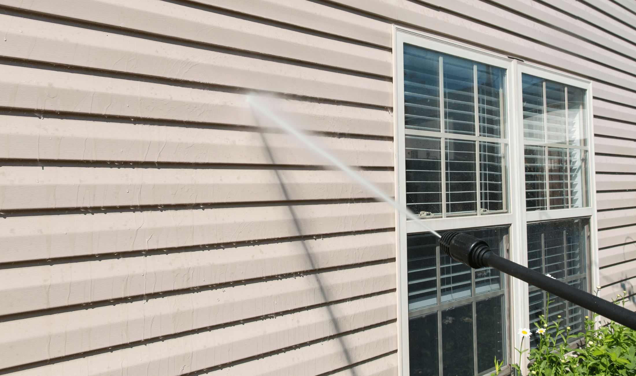 Someone pressure washing house siding.