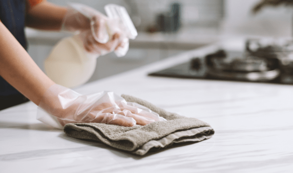 A gloved hand wiping down a kitchen counter.