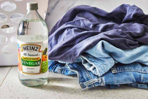 A stack of semi-folded clothes next to a bottle of vinegar.