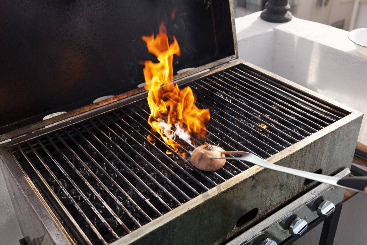 A flaming grill being cleaned with an onion.