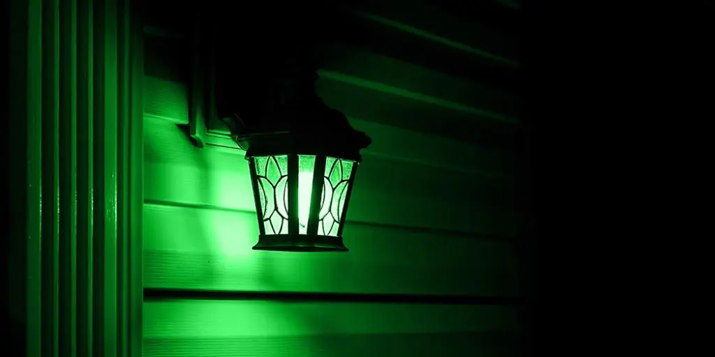 A porch light with a green bulb in it.