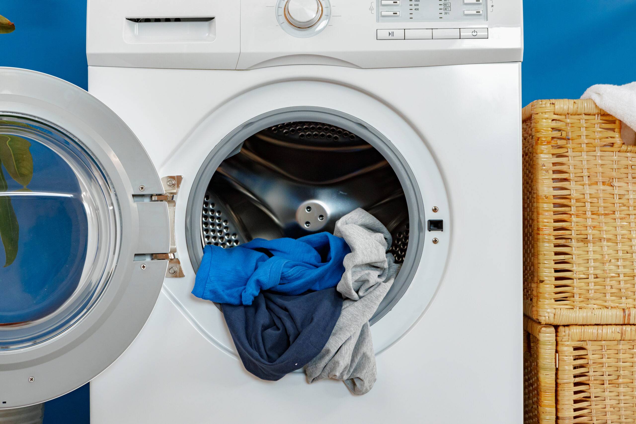 Laundry room. Close up of washing machine against blue wall