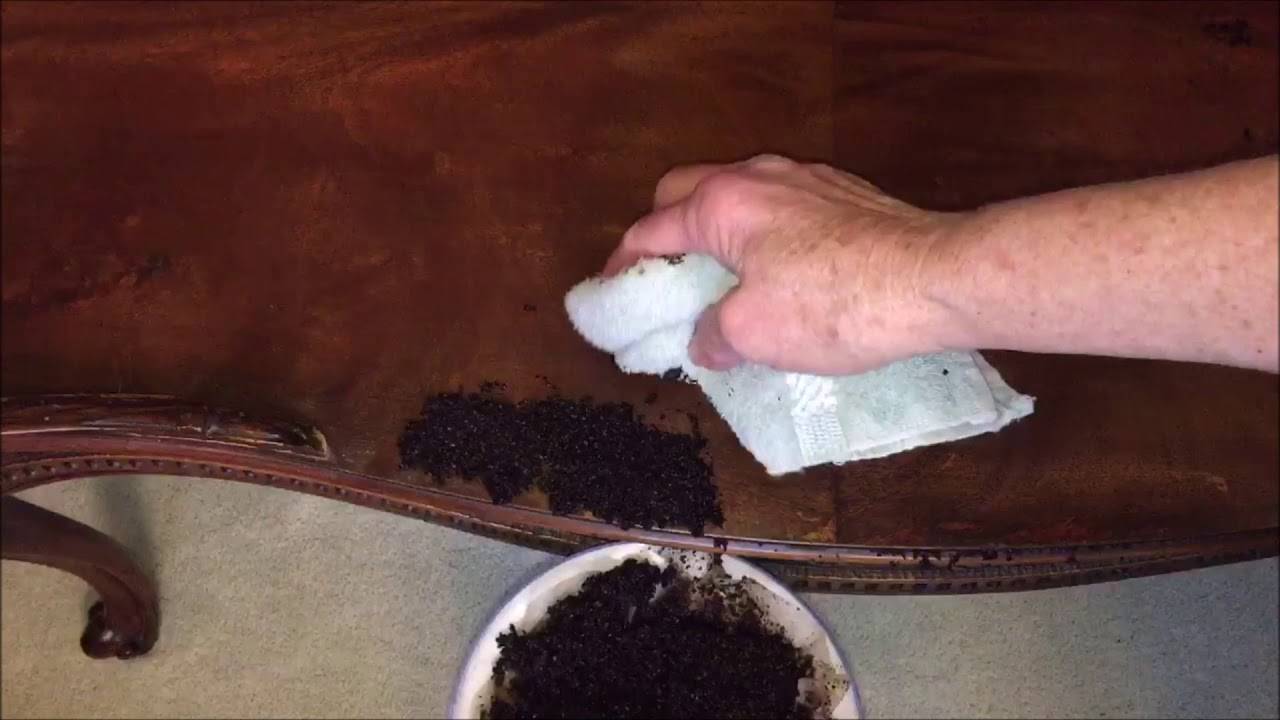 Someone wiping off coffee grounds they had poured onto a coffee table.
