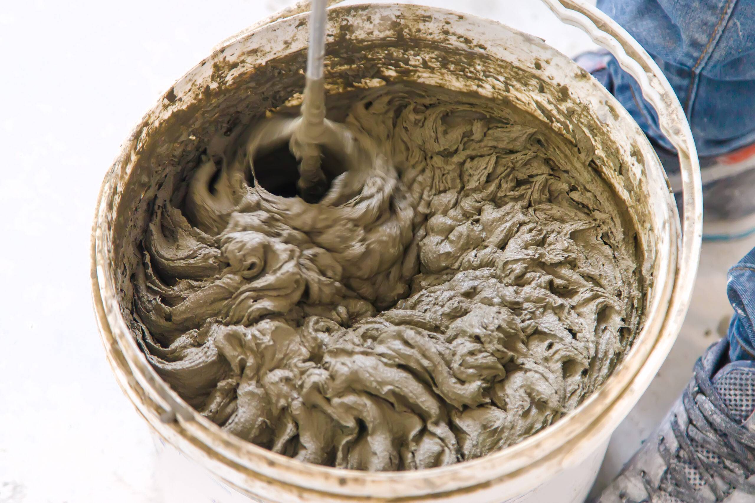 Mix the repair mortar in a bucket. Selective focus. White.