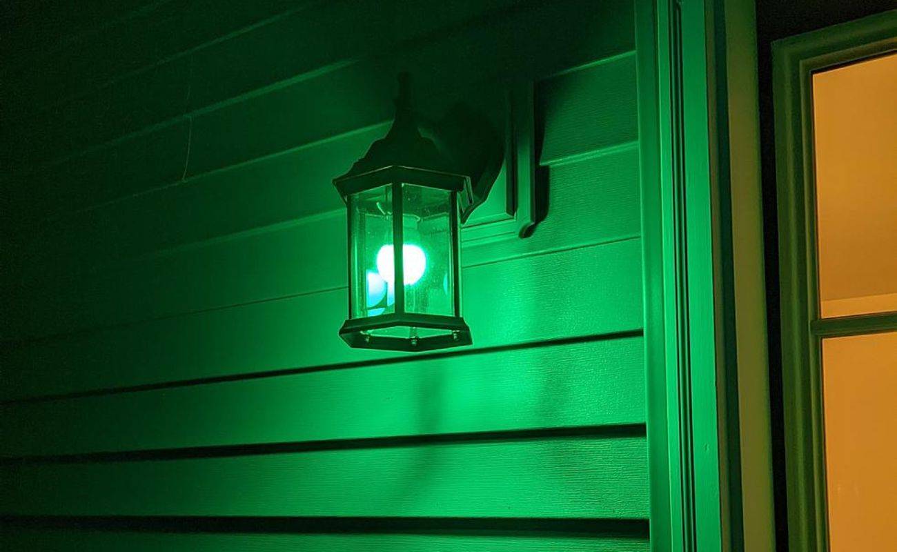 A porch light with a green bulb in it.