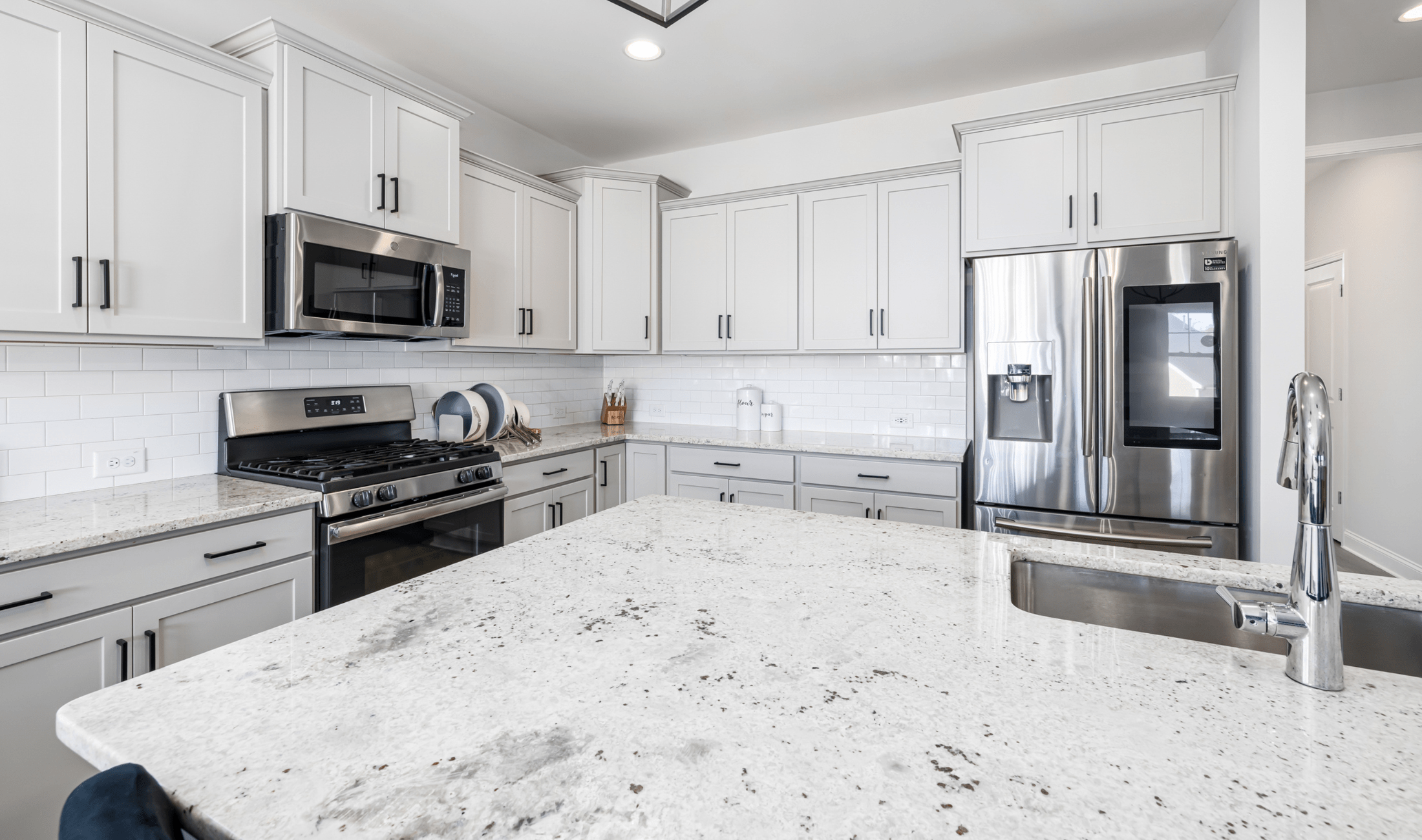 A bright white kitchen with quartz countertops.