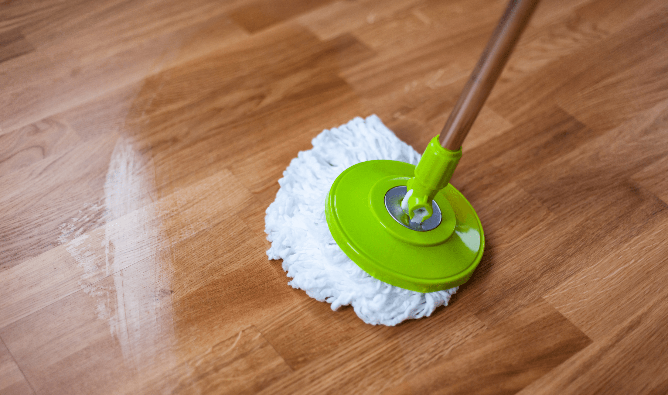 A spin mop mopping a wooden floor.