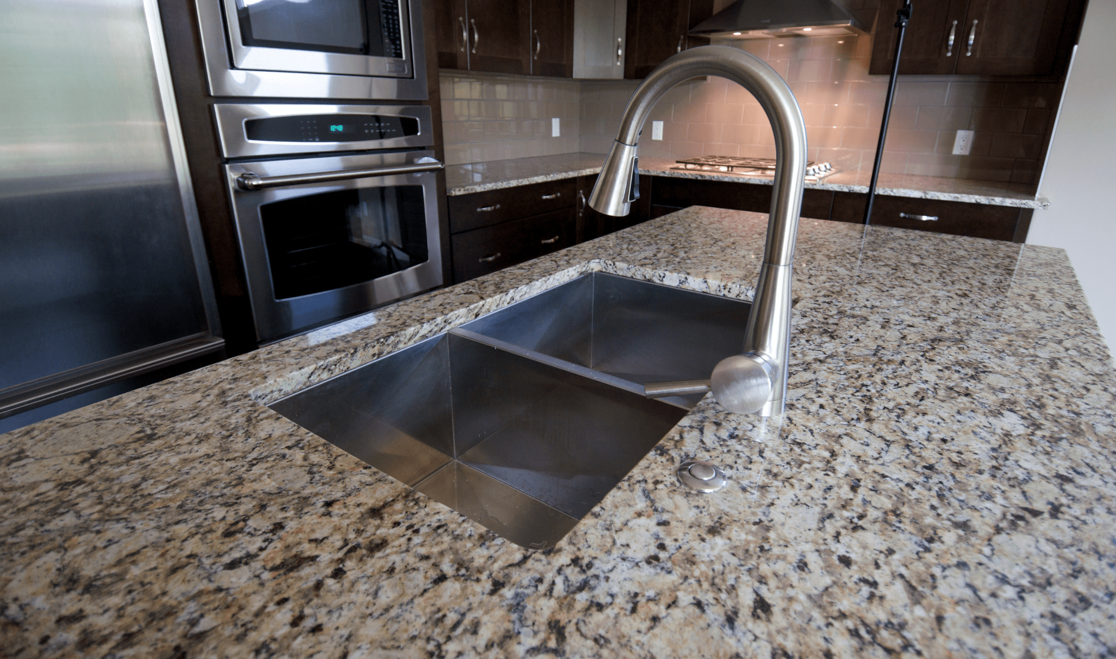A dark kitchen with a granite countertop.