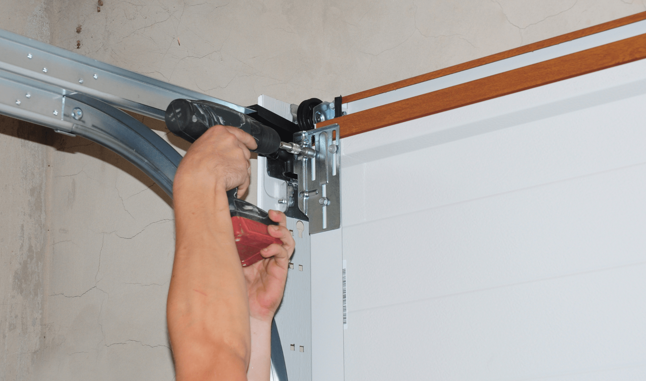 A person drilling into a component of a garage door.