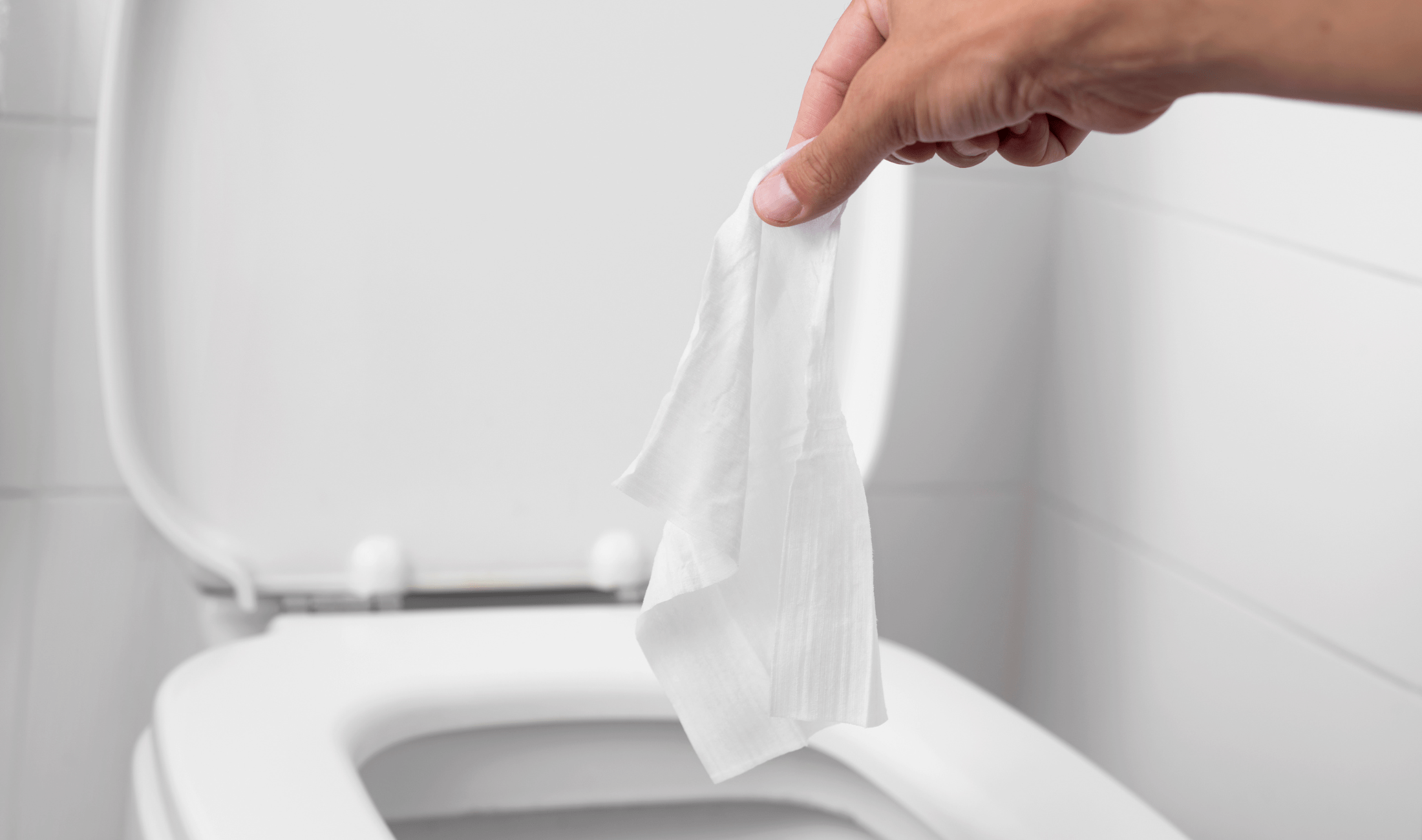 A person holding a wipe above a toilet.
