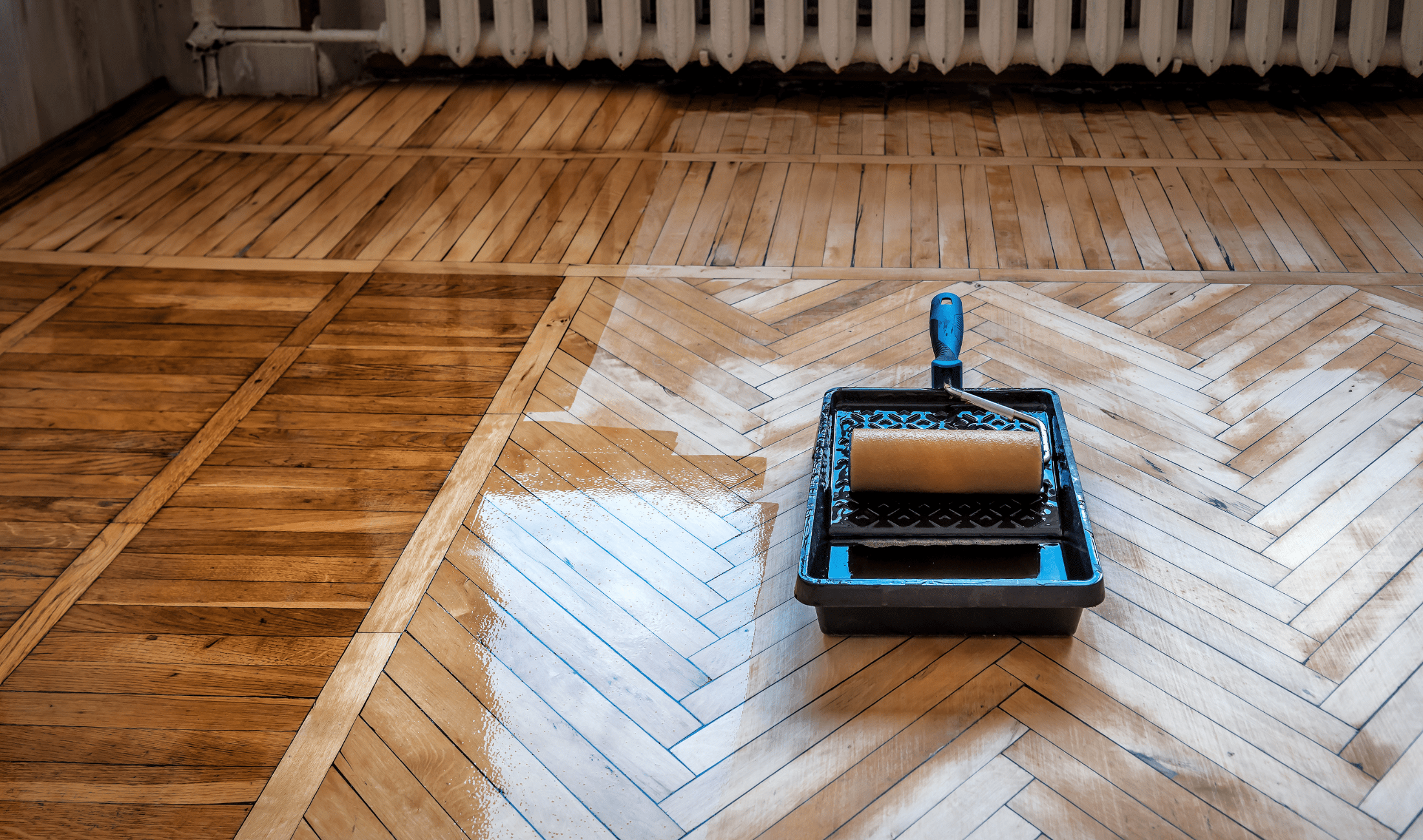A wooden floor that's been freshly varnished, the tray and roller visible.
