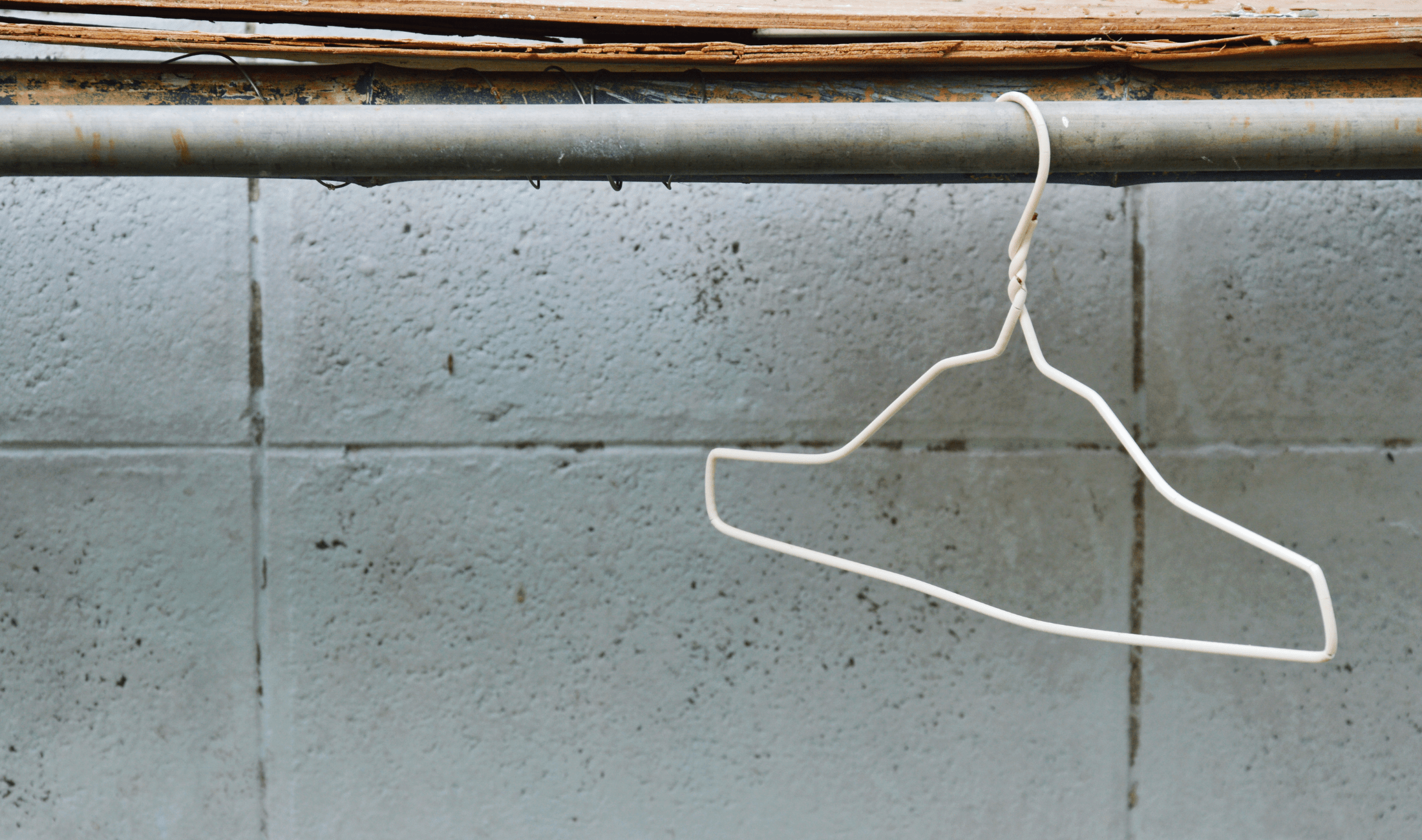 A wire hanger hanging from a pipe.