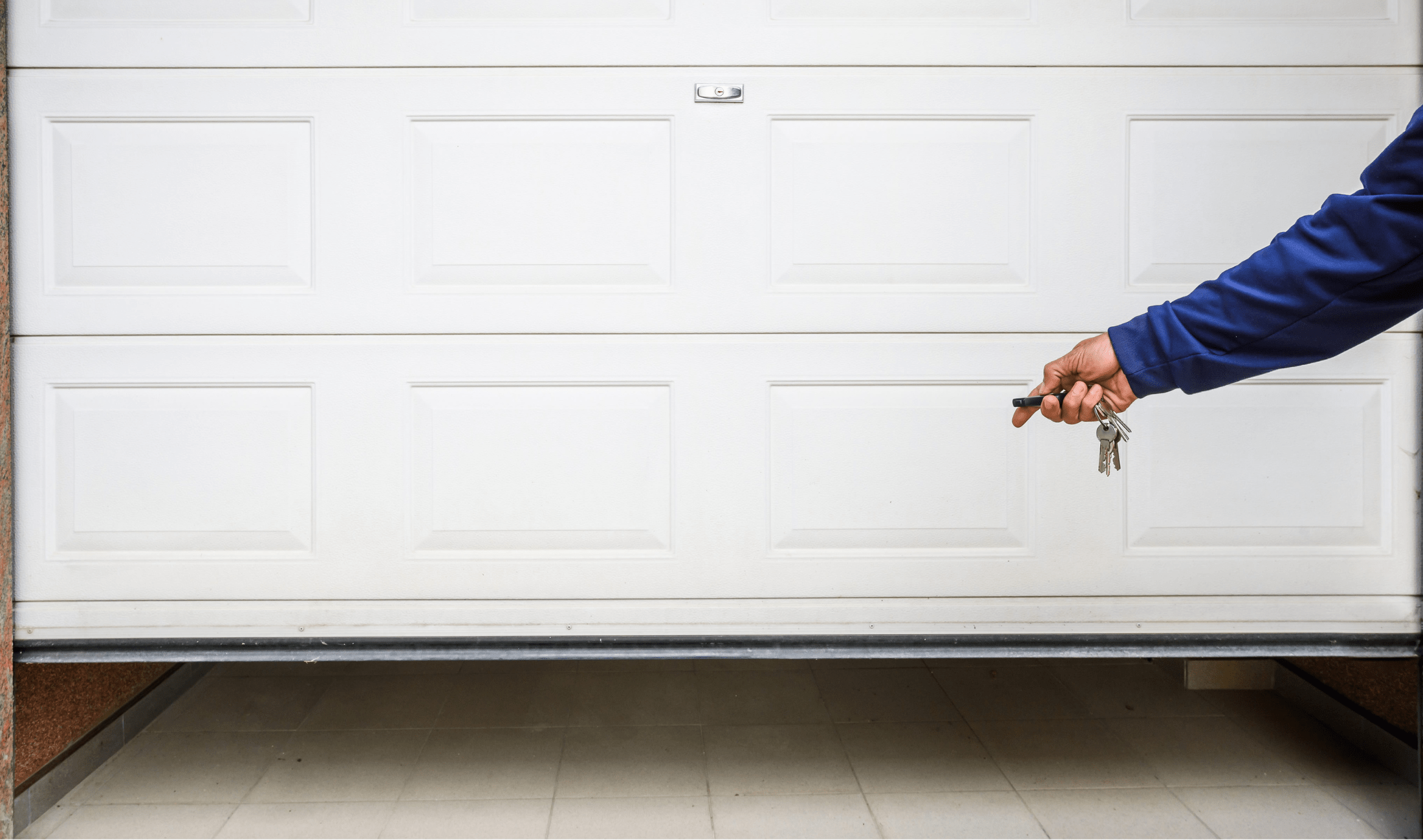 A white garage door slightly open with a hand in frame holding a remote door opener.