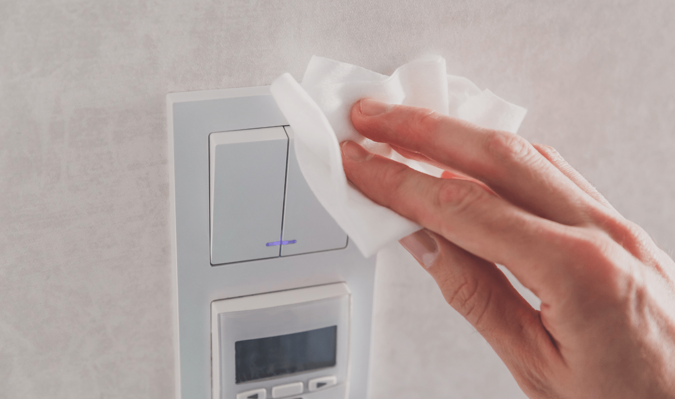 A person wiping a light switch with a tissue.
