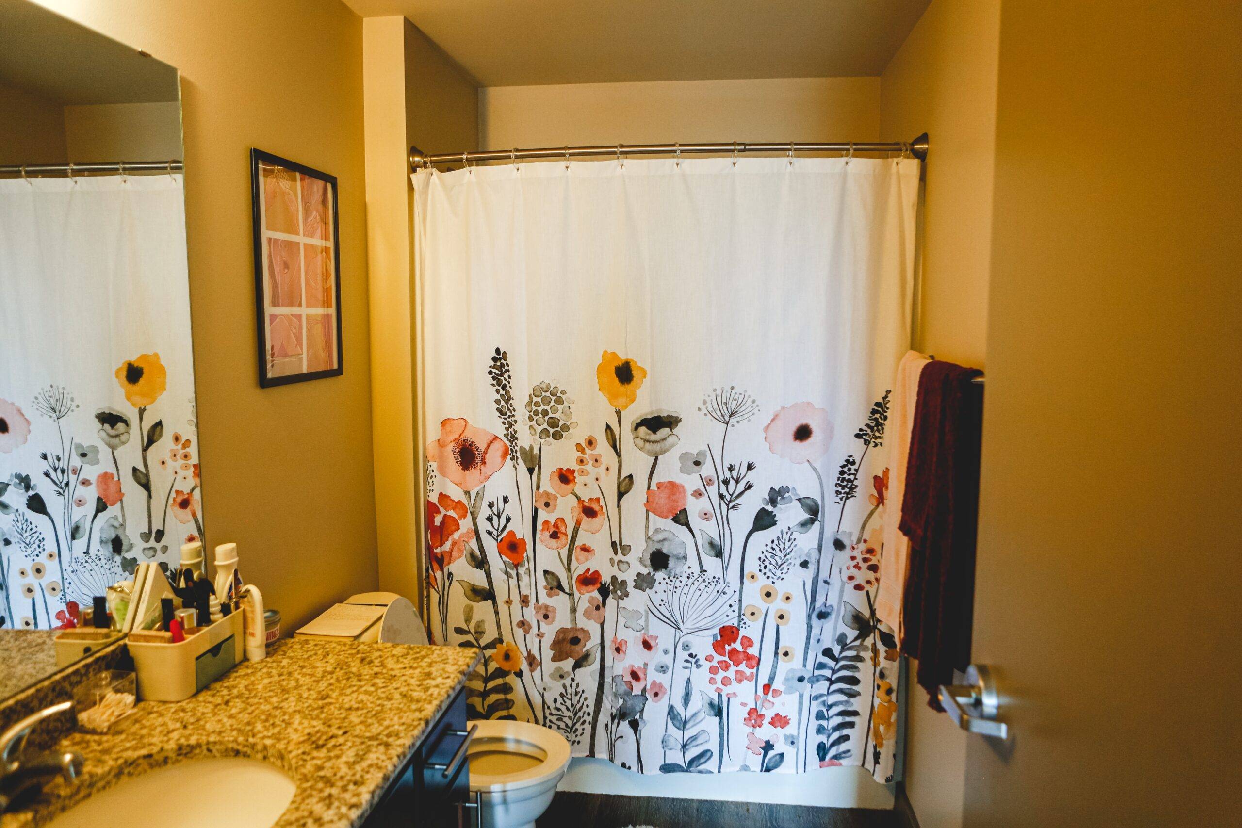 A bathroom with a flowery shower curtain.