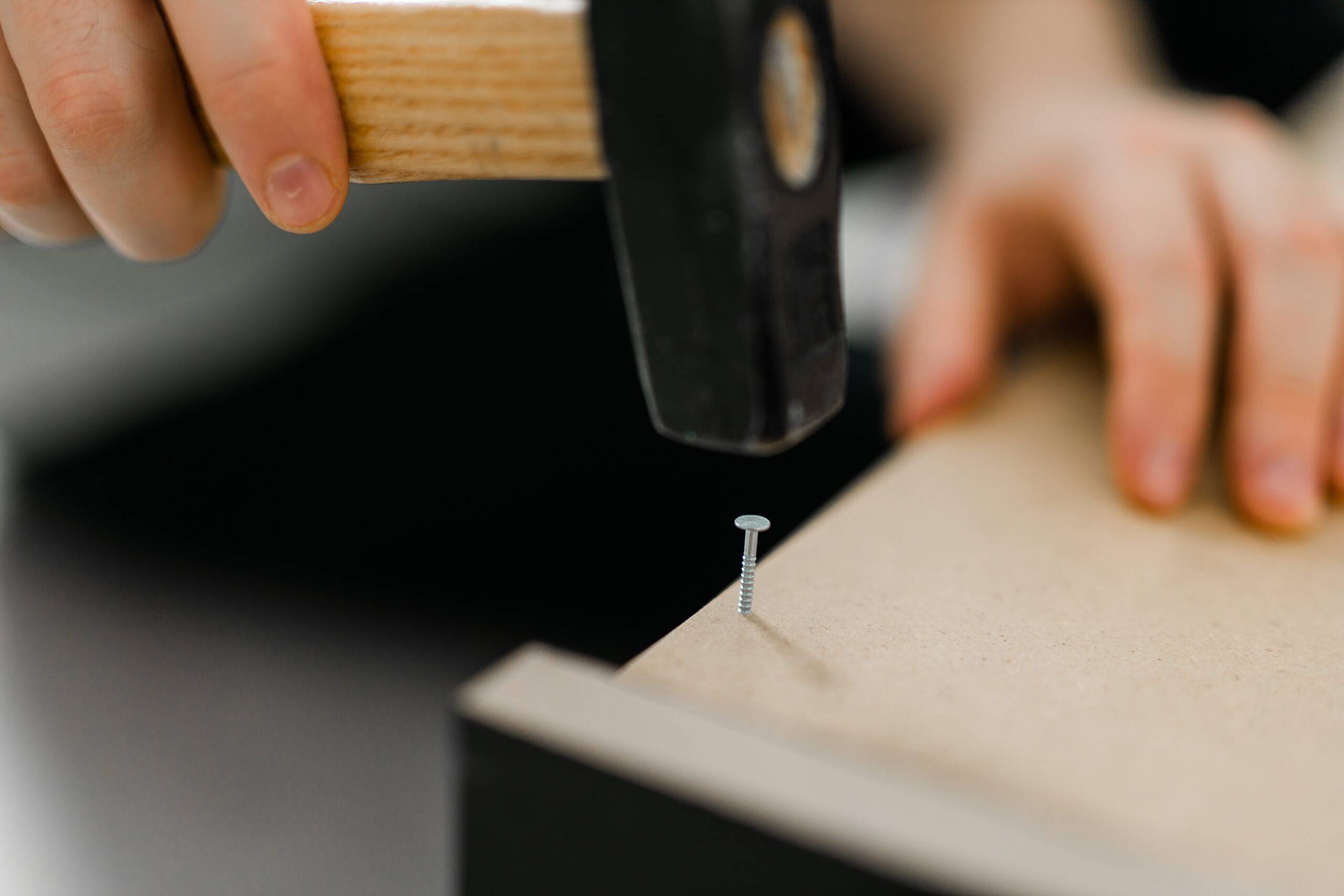 Close-up of hammering a nail into wooden board