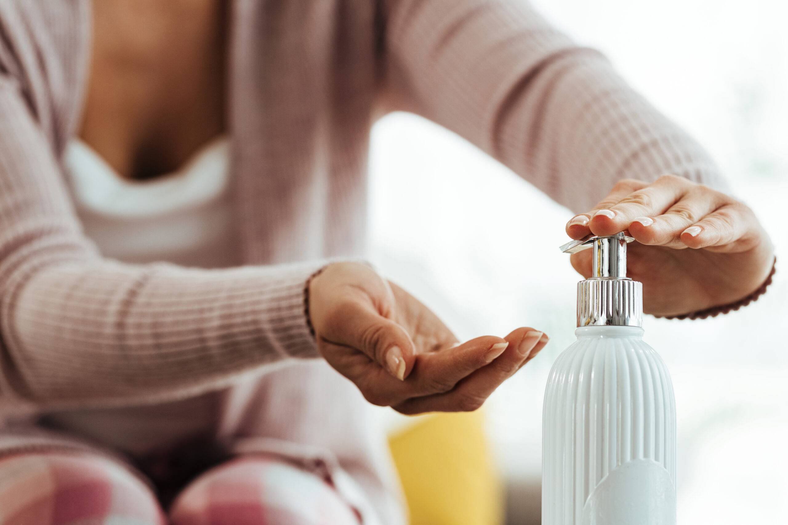Close-up of woman cleaning her hands with antiseptic hand gel at home.