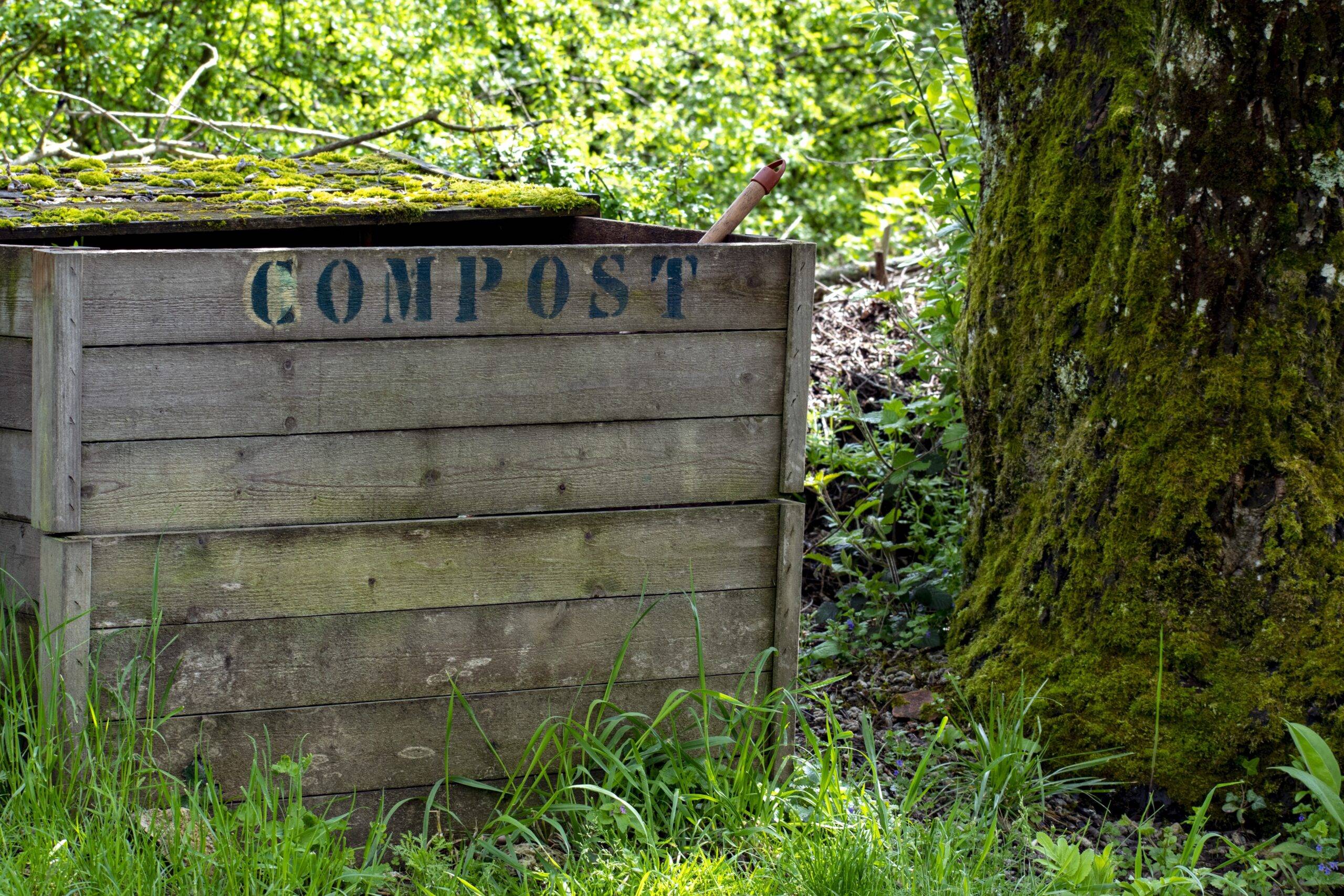 A large, homemade compost box in a person's yard.