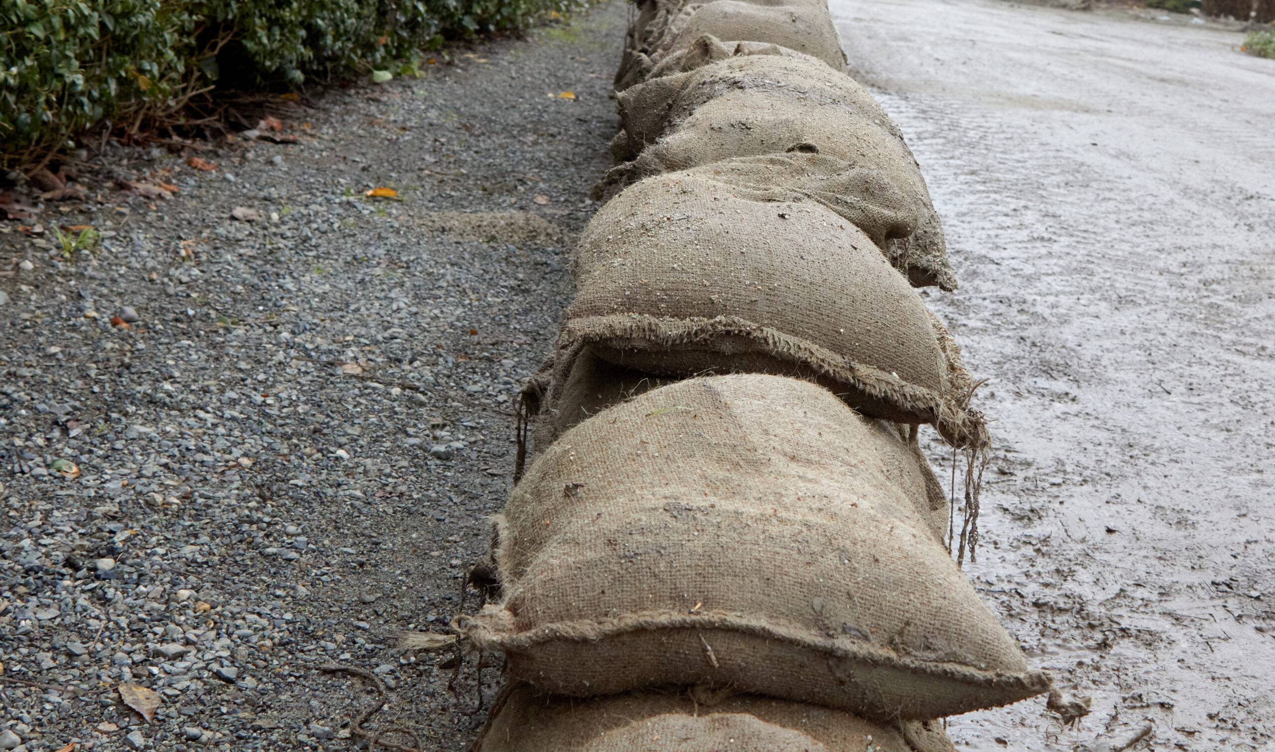 A bunch of sandbags are at the side of the road.