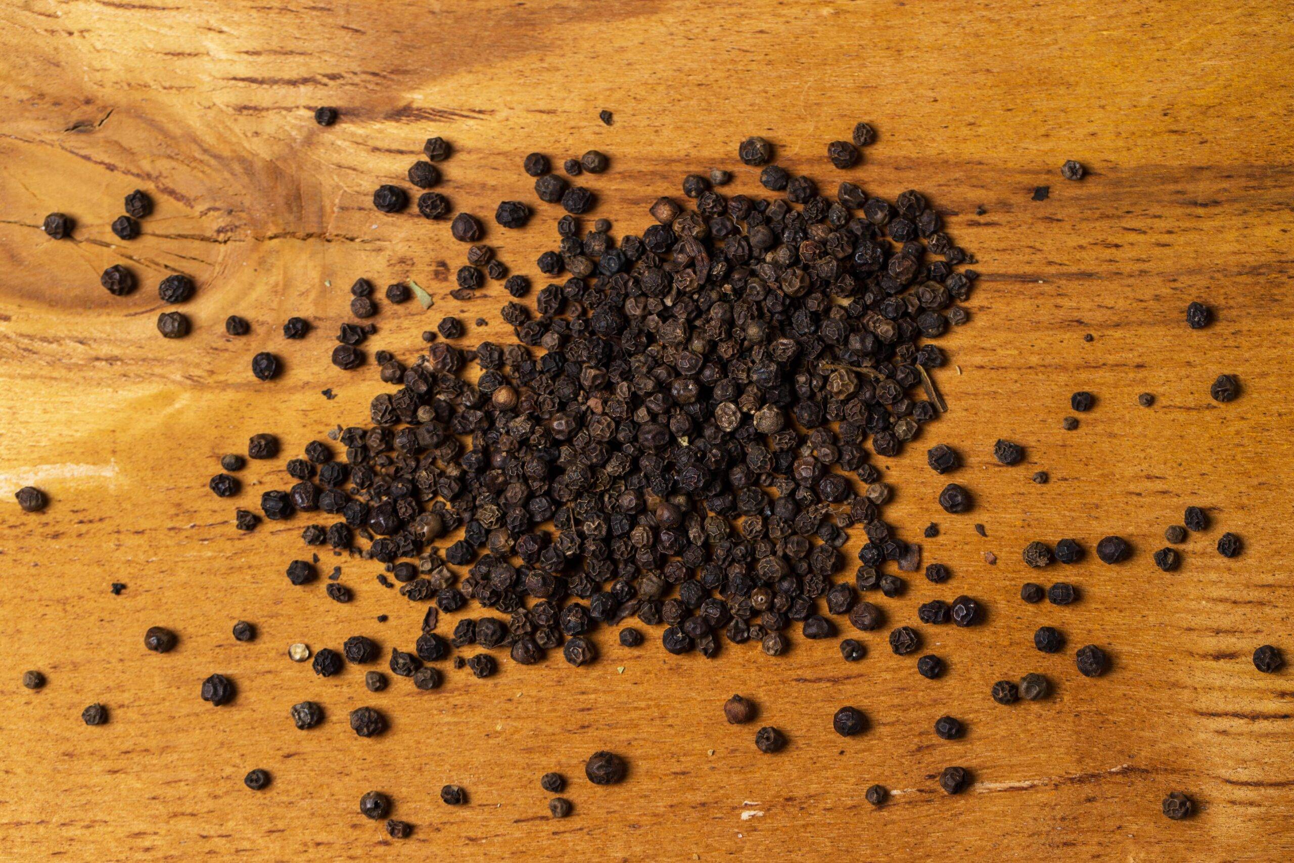 A pile of peppercorns on a wooden countertop.