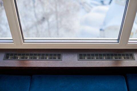 Windowsill, heating grid ventilation. Winter apartment heating. Modern double glazed windows
