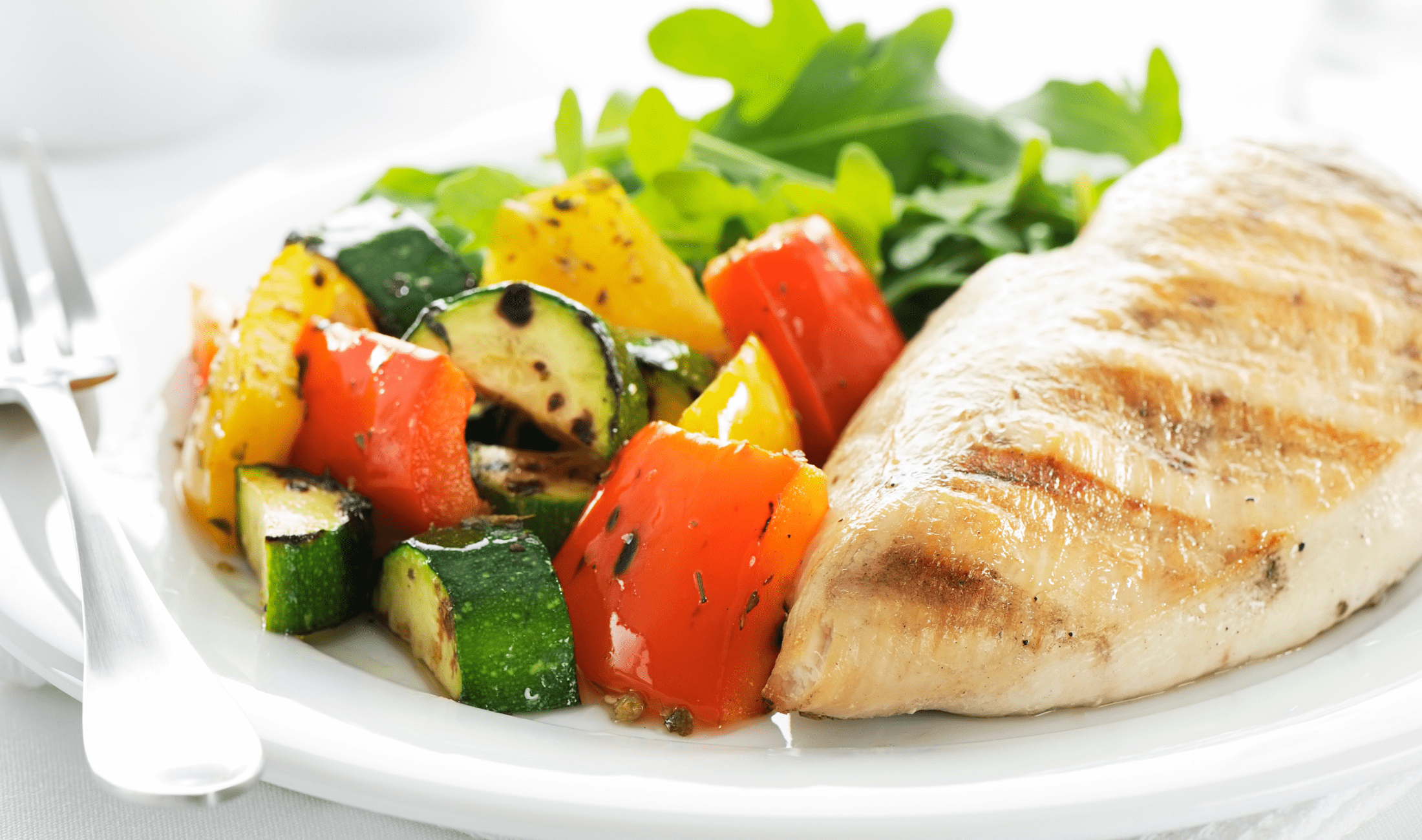 A healthy meal of chicken and diced veggies on a plate.
