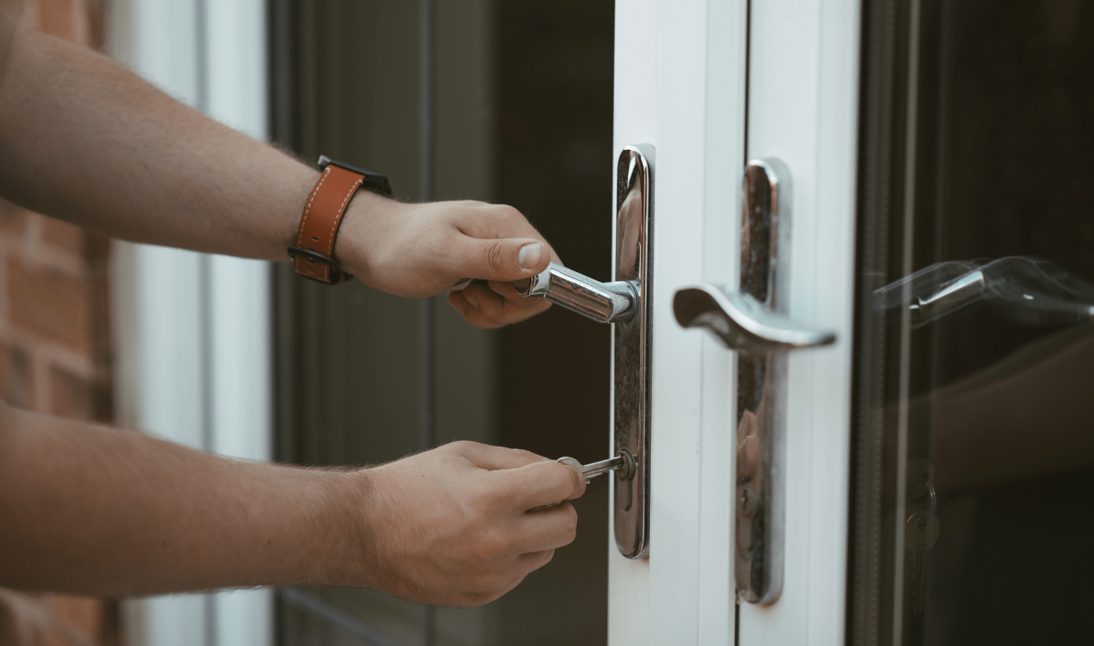 A person using a key and turning a door handle.