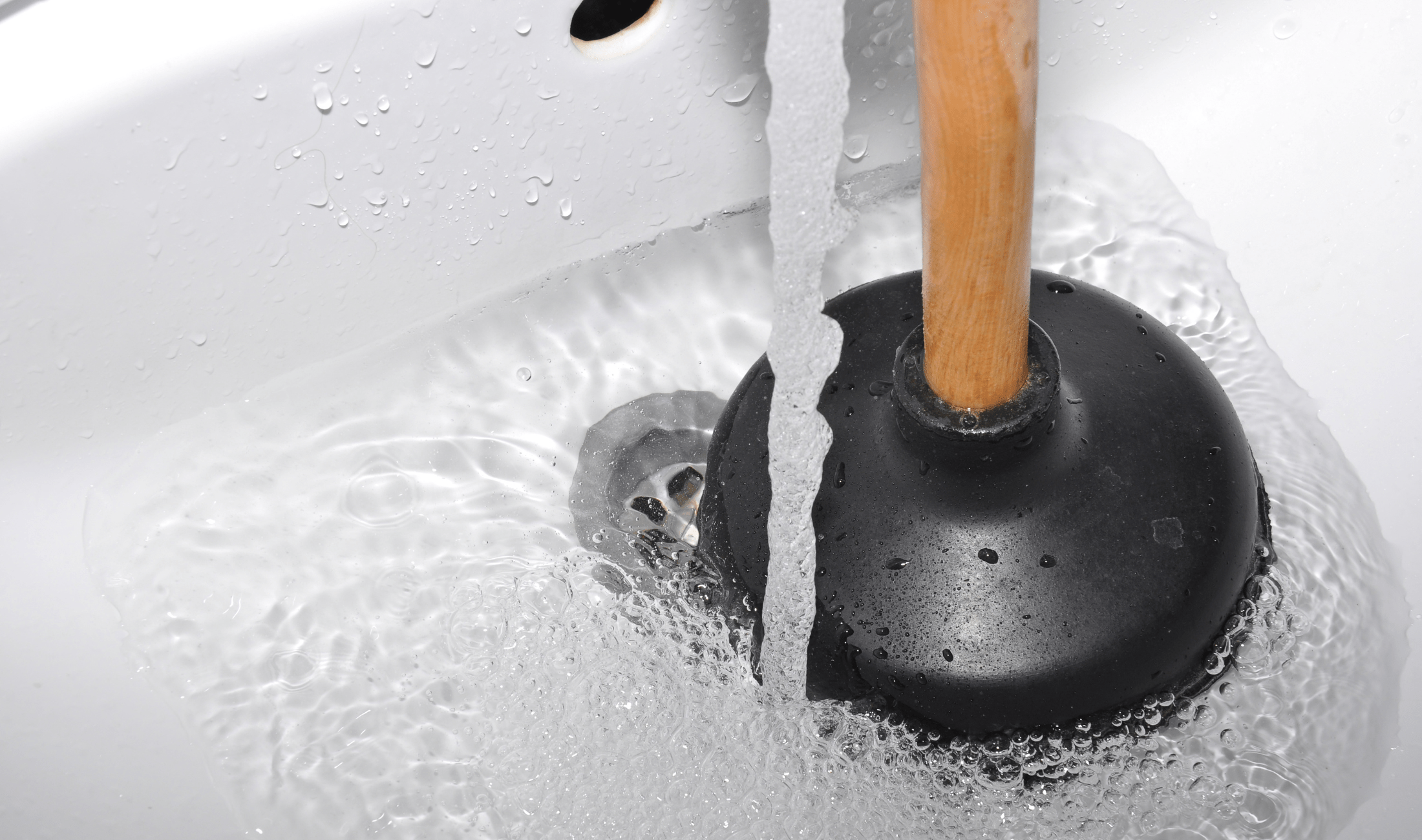 A close photo of a plunger being used on a sink drain.