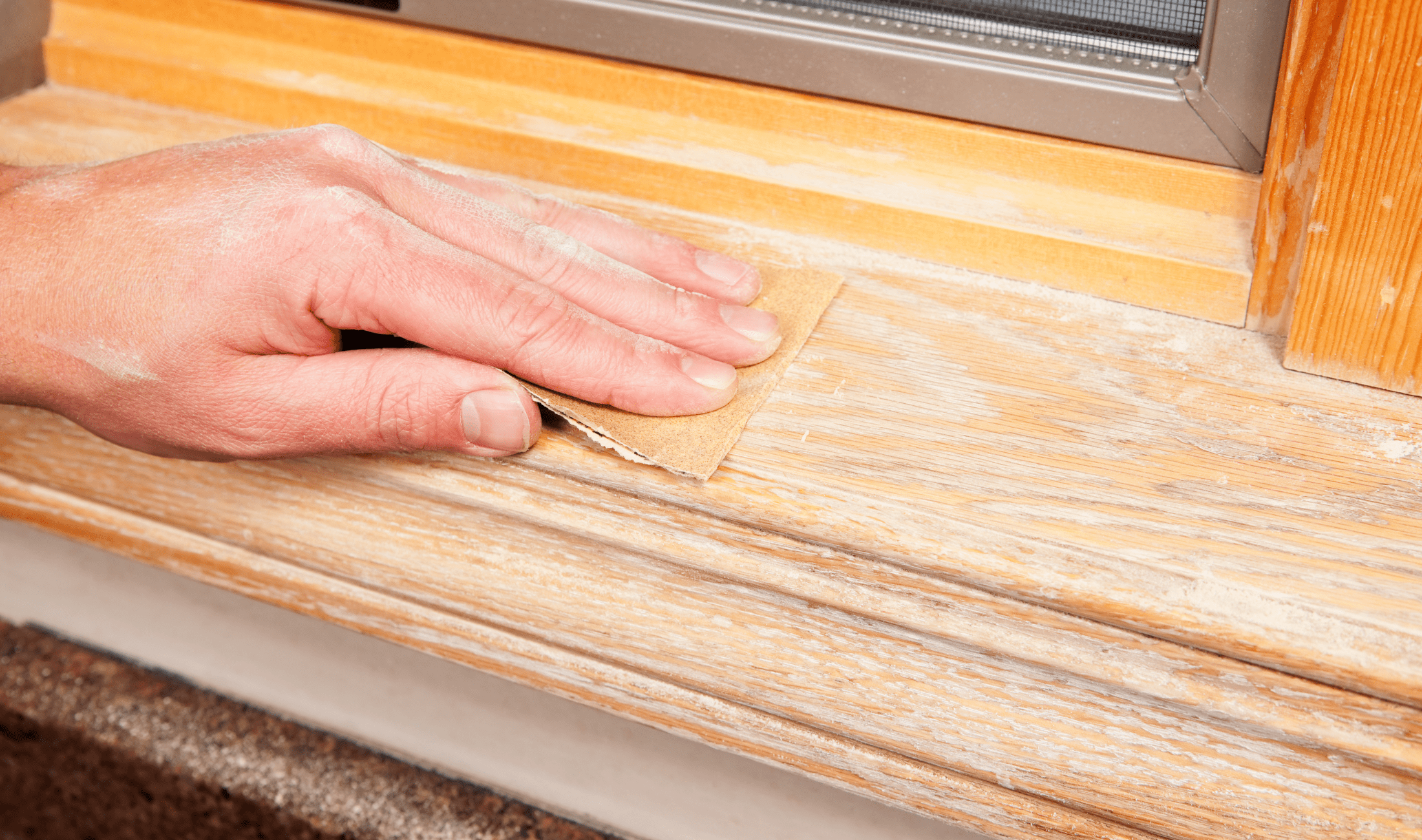 A person sanding a windowsill.