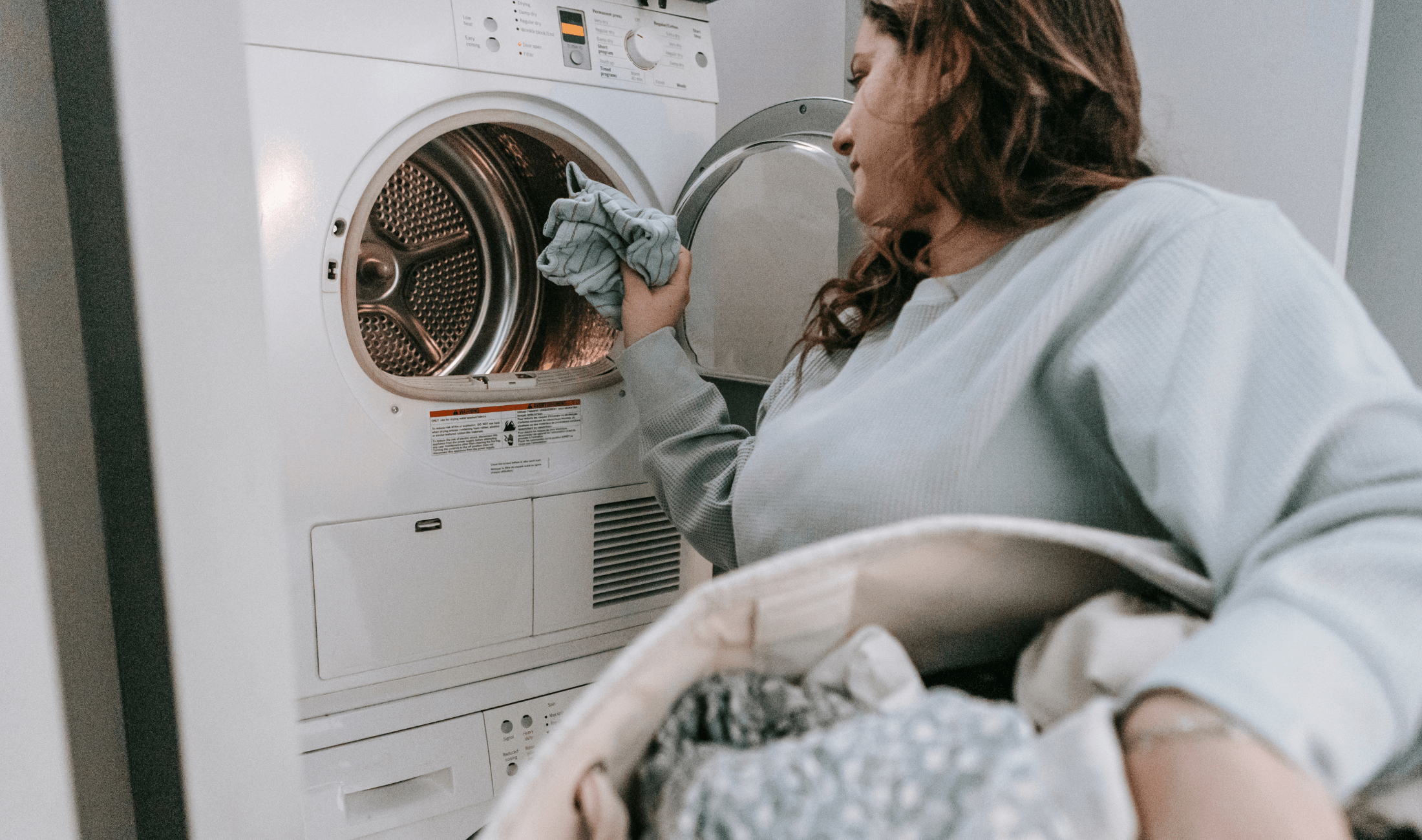 A woman putting clothes in a front-loading washing machine.