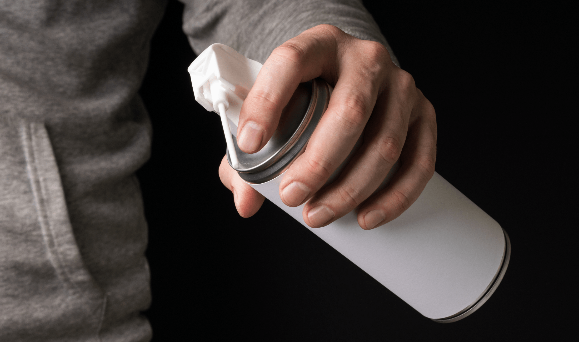 A hand holding a compressed air can.