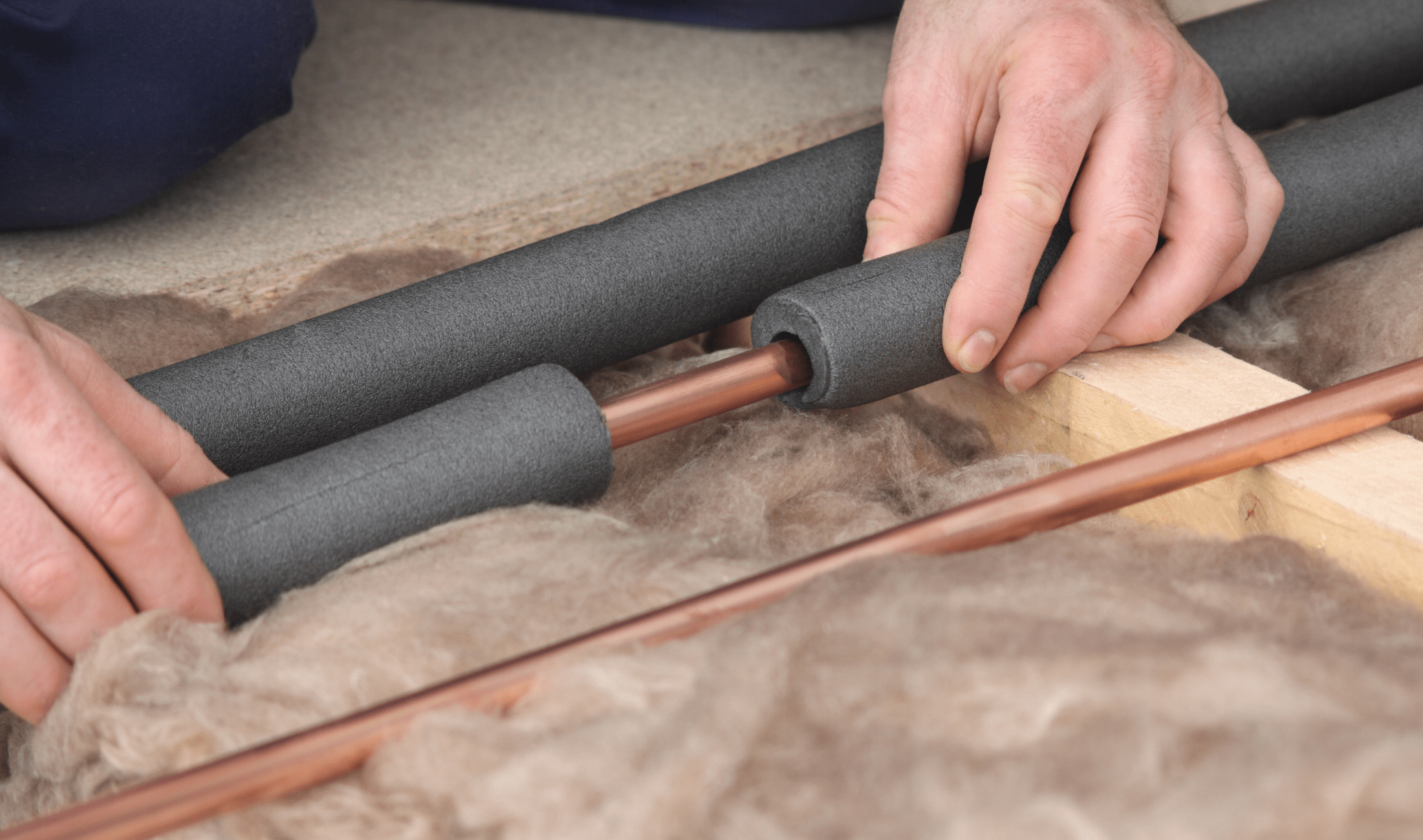 A person putting insulator foam over pipes.
